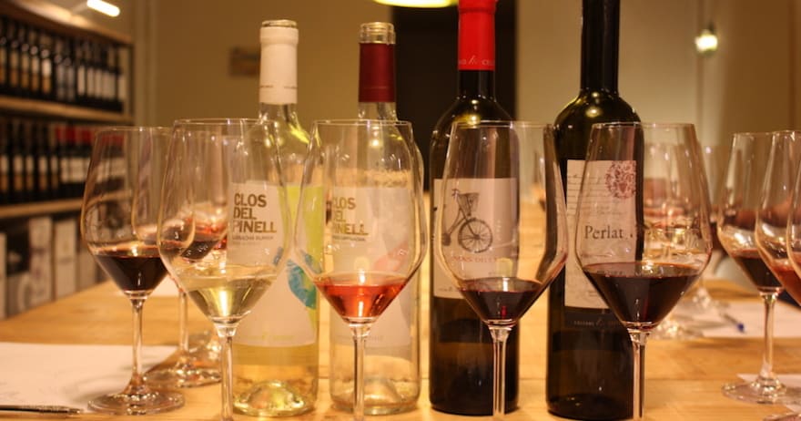 Las muestras de Cata de vinos en Barcelona se presentan elegantemente dispuestas con botellas de vino y copas sobre una mesa en una bodega cerca de las encantadoras calles de Barcelona. - ForTwo - Planes para parejas