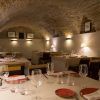 El Menú Aljibe del Restaurante Alacena de las Monjas (Granada) ofrece una acogedora experiencia gastronómica con mesas elegantemente dispuestas y platos de autor rojos bajo un techo de ladrillo arqueado, evocando el encanto de un aljibe escondido en Granada. - ForTwo - Planes para parejas