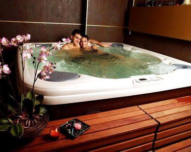 Una pareja relajada en un "Jacuzzi privado con tu pareja + cava + bombones", rodeados de orquídeas, a la luz de las velas en un banco de madera, disfrutando de cava burbujeante y deliciosos bombones. - ForTwo - Planes para parejas