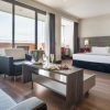 Descubre la elegancia de la Junior Suite: el secreto de Ilunion Hotels (Barcelona), con un diseño moderno que incluye una amplia cama, acogedora zona de estar, balcón y una mesa preparada con snacks y champán frío. - ForTwo - Planes para parejas
