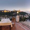 Disfrute de una cena romántica en el Restaurante Las Tomasas, donde la terraza ofrece impresionantes vistas del castillo de Granada iluminado en la colina lejana al atardecer. - ForTwo - Planes para parejas