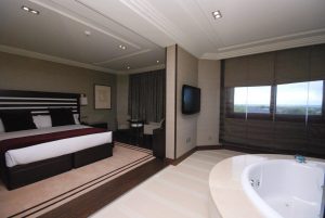 Alójese en una habitación contemporánea en el Hotel Los Peñascales: disfrute de la máxima privacidad (Madrid), que cuenta con una cama King, TV montada en la pared, zona de estar y jacuzzi junto a grandes ventanales para disfrutar de la máxima experiencia de lujo y privacidad. - ForTwo - Planes para parejas