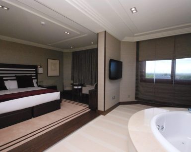 Alójese en una habitación contemporánea en el Hotel Los Peñascales: disfrute de la máxima privacidad (Madrid), que cuenta con una cama King, TV montada en la pared, zona de estar y jacuzzi junto a grandes ventanales para disfrutar de la máxima experiencia de lujo y privacidad. - ForTwo - Planes para parejas