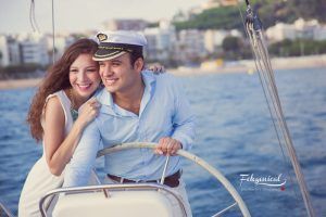 Una pareja, llena de alegría y amor por la aventura, navega en su velero cerca de la orilla en un día soleado, un momento perfecto para "Book de fotografía para parejas: Session Love". - ForTwo - Planes para parejas