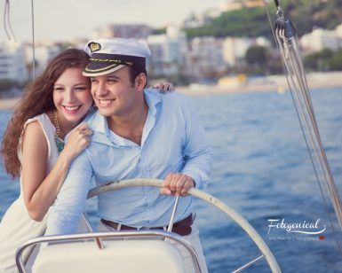 Una pareja, llena de alegría y amor por la aventura, navega en su velero cerca de la orilla en un día soleado, un momento perfecto para "Book de fotografía para parejas: Session Love". - ForTwo - Planes para parejas