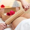 En un tranquilo entorno de spa en Valencia, una persona disfruta de un relajante masaje de piernas utilizando el Tratamiento de Maderoterapia en CosméticaClub Valencia, rodeado de delicados pétalos de rosa. - ForTwo - Planes para parejas