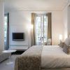 Habitación de lujo en el Hotel Hospes Puerta de Alcalá 5 estrellas Madrid, que ofrece una cama grande, espejo decorativo, sofá, TV y una ventana con cortinas. - ForTwo - Planes para parejas