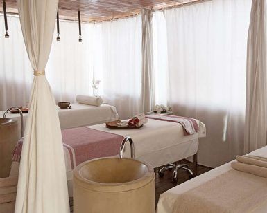 La Escapada Romántica con cena en habitación y spa (Alicante) ofrece una serena sala de spa con mesas de masaje, iluminación suave y cortinas blancas para mayor privacidad, creando la escapada romántica perfecta. - ForTwo - Planes para parejas