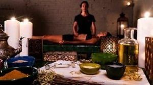 En una serena escena de spa, una persona disfruta de un masaje relajante mientras las velas titilan suavemente. Las ricas fragancias de los aceites Ritual Ancient Argal en Aire de Barcelona impregnan el ambiente, realzando la tranquilidad de este ritual, con cuencos y botellas elegantemente dispuestos en primer plano. - ForTwo - Planes para parejas
