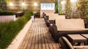 El restaurante Mastropiero Gastrobar en Cáceres cuenta con un patio en la azotea con sofás blancos en una terraza de madera, vegetación en macetas y mesas con sillas, creando un ambiente de gastrobar ideal. - ForTwo - Planes para parejas