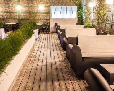 El restaurante Mastropiero Gastrobar en Cáceres cuenta con un patio en la azotea con sofás blancos en una terraza de madera, vegetación en macetas y mesas con sillas, creando un ambiente de gastrobar ideal. - ForTwo - Planes para parejas