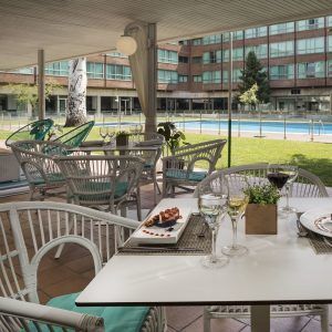El Day pass “Pool gourmet” del Hotel Meliá Barajas (Madrid) ofrece acceso a un elegante patio exterior con mesas y sillas junto a una resplandeciente piscina, perfecto para disfrutar de comida y bebidas gourmet mientras contempla las vistas a la exuberante zona verde y al señorial edificio. - ForTwo - Planes para parejas