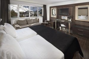 Una moderna habitación del Hotel Meliá Sol y Nieve en Sierra Nevada (Granada) incluye una cama doble, sofá, escritorio y ofrece impresionantes vistas a Sierra Nevada a través de grandes ventanales. - ForTwo - Planes para parejas