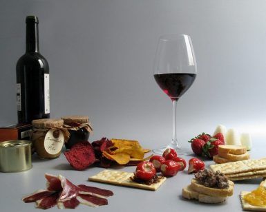 Una copa de vino, galletas, embutidos, fresas y diversos untables crean el montaje del Menú Campo con una botella de vino de fondo, ideal para un delicioso Picnic en Barcelona. - ForTwo - Planes para parejas