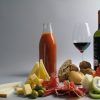 La mesa de picnic está preparada con un delicioso banquete que incluye vino, zumo, quesos, aceitunas, pan, jamón, sandía y kiwi: un Picnic en Barcelona por sorpresa - Menú Mediterráneo perfecto. - ForTwo - Planes para parejas