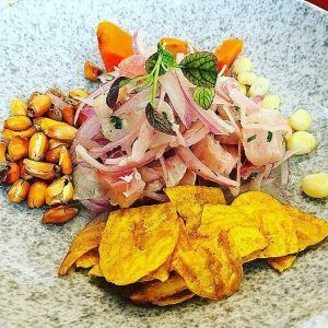 El ceviche peruano con chips de maíz y plátano macho en un plato texturizado ofrece un sabor de la cocina peruana ideal para el Menú degustación peruana en Aroma y Sabor (Tenerife). - ForTwo - Planes para parejas