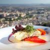 El plato de pescado gourmet, las verduras vibrantes y el paisaje urbano de fondo capturan perfectamente la esencia de Granada en el Hotel Alhambra Palace en el entorno "Almuerzo romántico a la carta". - ForTwo - Planes para parejas