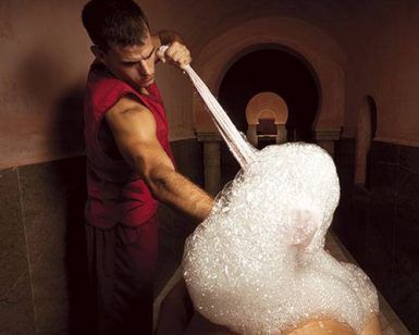 En un spa poco iluminado y con techos abovedados que recuerdan a Al Ándalus, alguien disfruta de MIDRA por Hammam Al Ándalus Granada, un masaje espumoso que le transporta a los tranquilos Hammams de Granada. - ForTwo - Planes para parejas