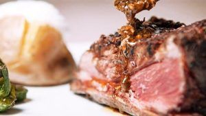 Un jugoso filete preparado por expertos en el Restaurante Milo Grill de Barcelona, rociado con salsa y servido con patatas asadas y verduras verdes. - ForTwo - Planes para parejas