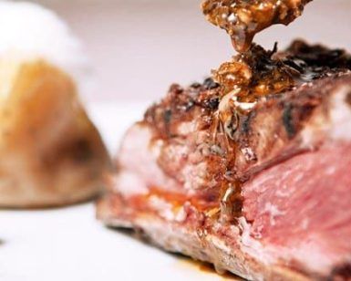 Un jugoso filete preparado por expertos en el Restaurante Milo Grill de Barcelona, rociado con salsa y servido con patatas asadas y verduras verdes. - ForTwo - Planes para parejas