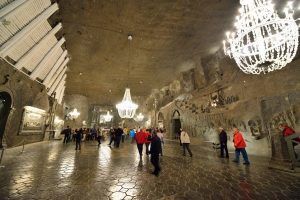 Los visitantes exploran la fascinante cámara subterránea de las minas de sal de Wieliczka, iluminada por candelabros que resaltan las paredes de piedra tallada, durante una "Visita de 4 horas a las minas de sal de Wieliczka (Cracovia). - ForTwo - Planes para parejas