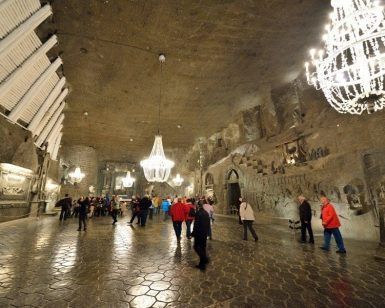 Los visitantes exploran la fascinante cámara subterránea de las minas de sal de Wieliczka, iluminada por candelabros que resaltan las paredes de piedra tallada, durante una "Visita de 4 horas a las minas de sal de Wieliczka (Cracovia). - ForTwo - Planes para parejas