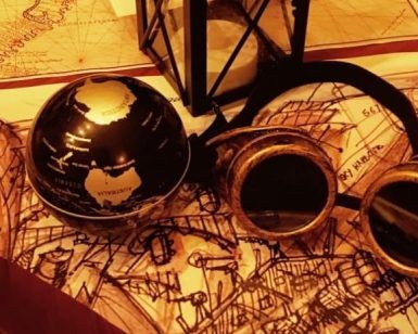 Las gafas vintage, la linterna y el globo terráqueo sobre una mesa con mapas y una pluma capturan el enigmático encanto de un Oopart. Ideal para Misión Oopart Escape Room Sevilla, este arreglo te invita a embarcarte en un viaje a través del tiempo y los artefactos perdidos. - ForTwo - Planes para parejas