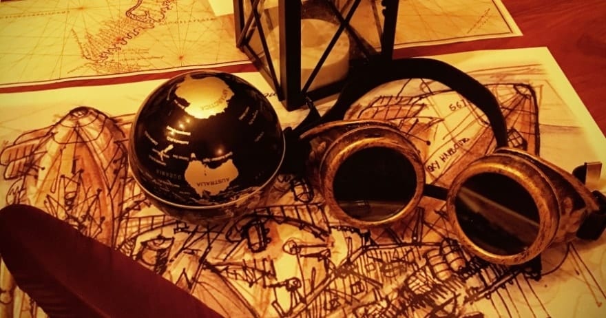 Las gafas vintage, la linterna y el globo terráqueo sobre una mesa con mapas y una pluma capturan el enigmático encanto de un Oopart. Ideal para Misión Oopart Escape Room Sevilla, este arreglo te invita a embarcarte en un viaje a través del tiempo y los artefactos perdidos. - ForTwo - Planes para parejas