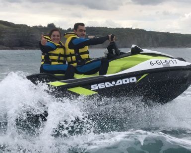 Dos personas, ataviadas con chalecos salvavidas amarillos, disfrutan de un emocionante paseo sobre las olas del océano cerca de los acantilados rocosos de Gijón con Excursión motos de agua (Gijón). - ForTwo - Planes para parejas