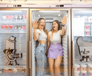 Dos mujeres ríen dentro de una gran nevera adornada con divertidas calcomanías de dibujos animados y envases de helado en el peculiar Museo Sweet Space de Madrid. ¡Compra tus "Entradas al Museo Sweet Space de Madrid" para vivir una experiencia encantadora!. - ForTwo - Planes para parejas
