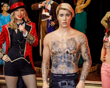 Las figuras de cera de una mujer con chaqueta roja y micrófono, y de un hombre tatuado, sin camisa y con pantalones negros, se alzan imponentes en el Museo de Cera de Madrid. Estas creaciones esculpidas de gran realismo forman parte de las impresionantes exposiciones que puedes explorar con tus Entradas al Museo de Cera de Madrid. - ForTwo - Planes para parejas