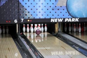 En Newpark Bowling: sala arcade con bolera (Barcelona), una bola de bolos rueda constantemente hacia los bolos, combinando la diversión clásica con el estilo moderno. - ForTwo - Planes para parejas