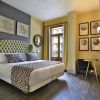 El NH Collection Colón en Valencia ofrece una elegante habitación con una cama grande adornada con cojines estampados, obras de arte enmarcadas, un espejo redondo y una ventana con encantadoras vistas a la calle. Disfrute de comodidad y sofisticación durante su estancia. - ForTwo - Planes para parejas