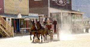 Una diligencia tirada por dos caballos recorre un polvoriento pueblo del Oeste, que recuerda a Oasys, el parque temático del desierto de Tabernas (Almería). Ofrece una vívida mirada al pasado sin necesidad de entradas. - ForTwo - Planes para parejas