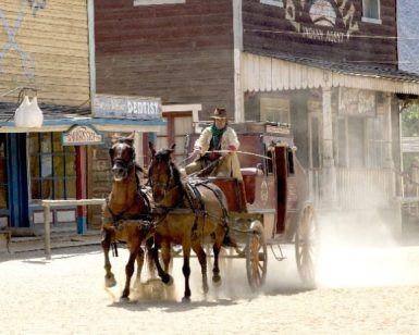 Una diligencia tirada por dos caballos recorre un polvoriento pueblo del Oeste, que recuerda a Oasys, el parque temático del desierto de Tabernas (Almería). Ofrece una vívida mirada al pasado sin necesidad de entradas. - ForTwo - Planes para parejas
