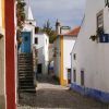 Explore las encantadoras calles adoquinadas, los edificios encalados, las puertas coloridas y las escaleras en el pintoresco pueblo de Óbidos en nuestra "Visita guiada a Óbidos y Fátima (Lisboa). - ForTwo - Planes para parejas