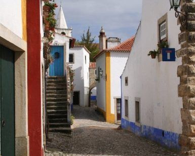 Explore las encantadoras calles adoquinadas, los edificios encalados, las puertas coloridas y las escaleras en el pintoresco pueblo de Óbidos en nuestra "Visita guiada a Óbidos y Fátima (Lisboa). - ForTwo - Planes para parejas