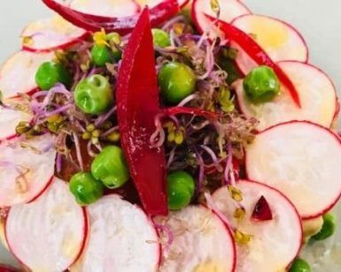En el restaurante romántico Ohlala Bistrot de Ibiza, la vibrante ensalada incluye rodajas de rábanos, guisantes, brotes y pimiento rojo dispuestos artísticamente en círculo: un plato perfecto para una salida nocturna. - ForTwo - Planes para parejas