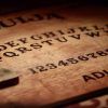 Un primer plano de la ouija de "Ouija - Un juego de Horror Box Escape Room (Barcelona)" presenta una plancheta, capturando la atmósfera inquietante de una sala de escape. El logo de Horror Box se esconde en una esquina, realzando la atmósfera escalofriante. - ForTwo - Planes para parejas