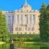 Explora el Palacio Real de Madrid, un palacio impresionante con una fachada detallada, rodeado de un jardín cuidadosamente mantenido, piscina reflectante y cielo azul claro. - ForTwo - Planes para parejas