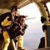 Dos personas sonríen mientras están bien sujetas a su paracaídas, disfrutando de un Salto tándem de paracaidismo con Skydive Empuriabrava mientras saltan en paracaídas desde un avión. - ForTwo - Planes para parejas
