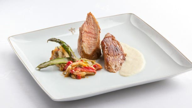 Un plato gourmet con dos suculentas carnes en salsa cremosa y verduras mixtas sobre un plato cuadrado blanco evoca las refinadas experiencias culinarias del Restaurante Torreorgaz Parador de Cáceres. - ForTwo - Planes para parejas