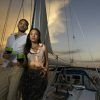 Una pareja disfruta de un romántico paseo en barco en la Herradura y Almuñécar, tomando bebidas mientras se deslizan por aguas serenas con velas puestas contra la vibrante puesta de sol. - ForTwo - Planes para parejas