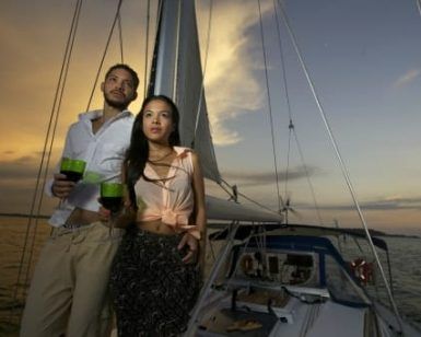 Una pareja disfruta de un romántico paseo en barco en la Herradura y Almuñécar, tomando bebidas mientras se deslizan por aguas serenas con velas puestas contra la vibrante puesta de sol. - ForTwo - Planes para parejas