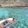 La gente nada cerca de un yate en las cristalinas aguas turquesas de una costa rocosa, ideal para "Sorprende a tu pareja con un paseo en catamarán" en Palma de Mallorca. - ForTwo - Planes para parejas