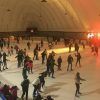 Una multitud animada disfruta de "Patinaje sobre hielo para dos en Igloo (Granada)" bajo el cálido resplandor de una pista iluminada por una cúpula, que recuerda a un iglú transportado a Granada. - ForTwo - Planes para parejas