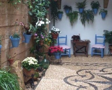 Explora el acogedor patio adornado con plantas en macetas, sillas azules y un diseño de piso de mosaico de guijarros que recuerda a los patios cordobeses en nuestro "Tour guiado por los patios cordobeses". - ForTwo - Planes para parejas
