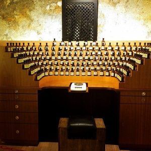 Un mostrador de madera en Crea tu perfume en El Patio de los Perfumes en Granada exhibe varios frascos de perfume pequeños, dispuestos de forma semicircular contra una pared texturizada. - ForTwo - Planes para parejas
