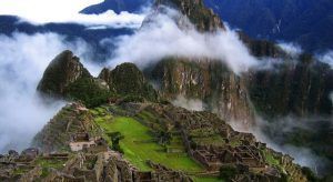 Una vista aérea de Machu Picchu muestra antiguas ruinas de piedra y terrazas verdes que se combinan armoniosamente entre picos brumosos: una imagen clásica del Viaje a Perú de 6 días. - ForTwo - Planes para parejas