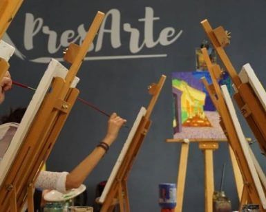 En una vibrante clase de arte, la gente pinta en caballetes debajo de la frase "Taller creativo de pintura de cuadros (Madrid)" en la pared, encarnando el espíritu de un taller creativo en Madrid. - ForTwo - Planes para parejas